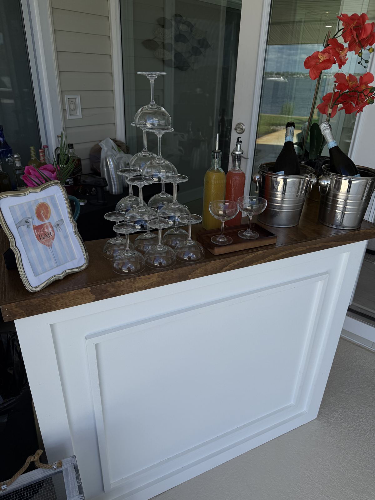 With A Twist mimosa bar setup with glass tower, ice buckets, and juice carafes at a waterfront event